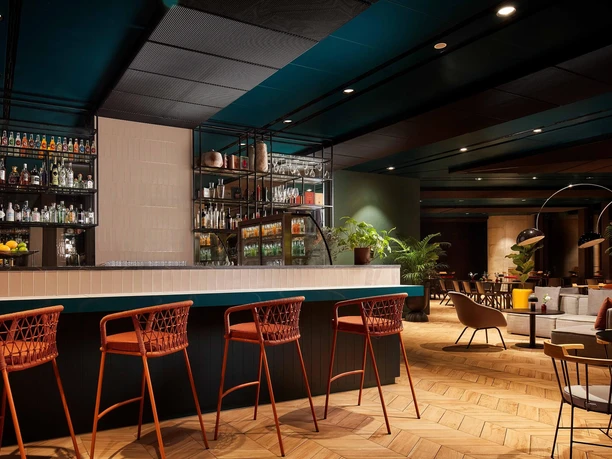 OAKS Bar im NH Collection Frankfurt Spin Moderne Bar mit roten Barhockern und vielfältigem Getränkeangebot.