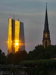 Dreikönigskirche Sonnenuntergang spiegelt sich in der gläsernen Fassade eines Hochhauses in Frankfurt.