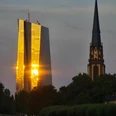 Dreikönigskirche Sonnenuntergang spiegelt sich in der gläsernen Fassade eines Hochhauses in Frankfurt.
