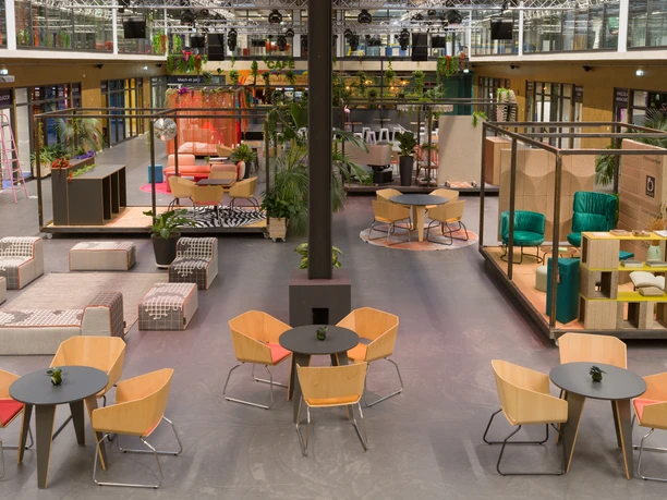 Köln-Mülheim Exklusiv Großer, moderner Veranstaltungsraum mit stilvollen Sitzbereichen, Pflanzen und farbiger Beleuchtung.