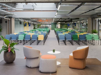 OG - Bühne Moderne Konferenzraumansicht mit bunten Stühlen, Glaswänden und Pflanzen, geeignet für Veranstaltungen.Modern conference room view with colorful chairs, glass walls and plants, suitable for events.