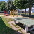 Uppen Brinke Das Bild zeigt einen kleinen Spielplatz mit einer Rutsche, einer Schaukel und einem alten Tischtennistisch.
