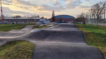 Pumptrack Bahn Rahden Der Pumptrack in Rahden zeigt eine kurvenreiche Strecke. Die Hügel aus Asphalt sind sanft geformt.
