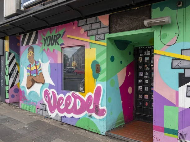 Veedel Club The picture shows a colorful graffiti façade in an urban environment with bright colors and shapes.
