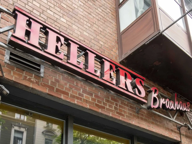 HELLERS Brewery The red neon sign "HELLERS Brauhaus" in front of a red brick façade during the day.