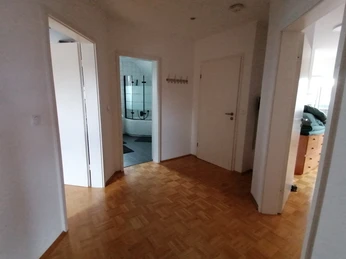 IMG_20250724_153325.jpg Flur in einer Wohnung mit Holzboden, Zugang zu Badezimmer, Schlafzimmer und einem weiteren Raum.