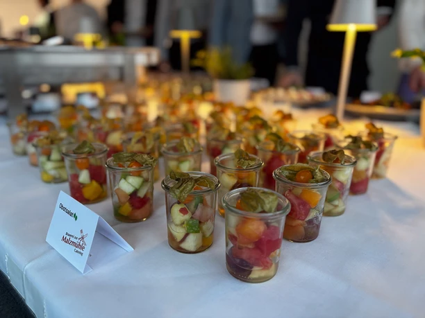Business Buffet Catering Ansprechend präsentiertes Buffet mit kleinen Gläsern gefüllt mit buntem Obstsalat, beleuchtet und stilvoll angerichtet.