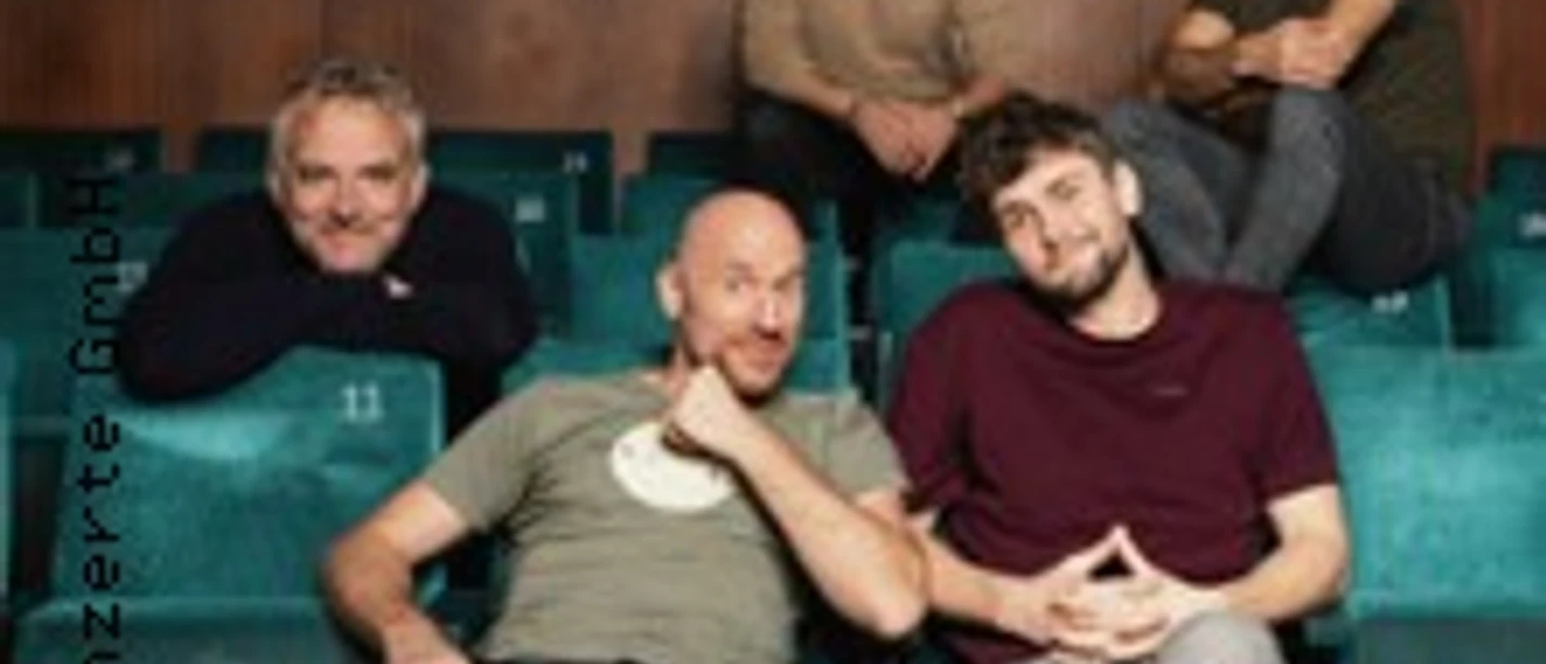 Ein fünfköpfiges A-cappella-Ensemble sitzt auf Theaterstühlen, lächelt entspannt in die Kamera.