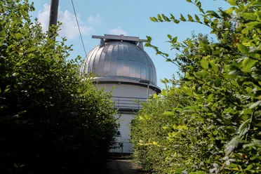 Blick auf die Kuppel der Sternwarte zwischen Büschen.