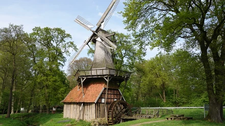 Hüvener Mühle, Wind- und Wassermühle an der Radde ©Emsland Tourismus GmbH (20).jpg Historische Wind- und Wassermühle aus Holz mit rotem Ziegeldach, umgeben von grünen Bäumen.