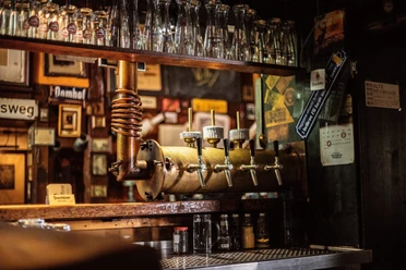 Kneipe Alte Heuwaage Gütersloh Historische Zapfanlage mit mehreren Hähnen, darüber Reihen sauberer Biergläser an der Theke.