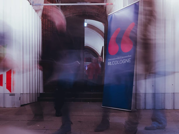 lit.COLOGNE People walk past a banner with the inscription "lit.COLOGNE".