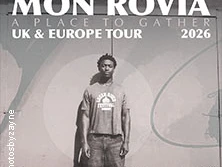 Musiker Mon Rovîa posiert vor einer grauen Wand mit Tour-Daten und Titel "A Place to Gather 2026".