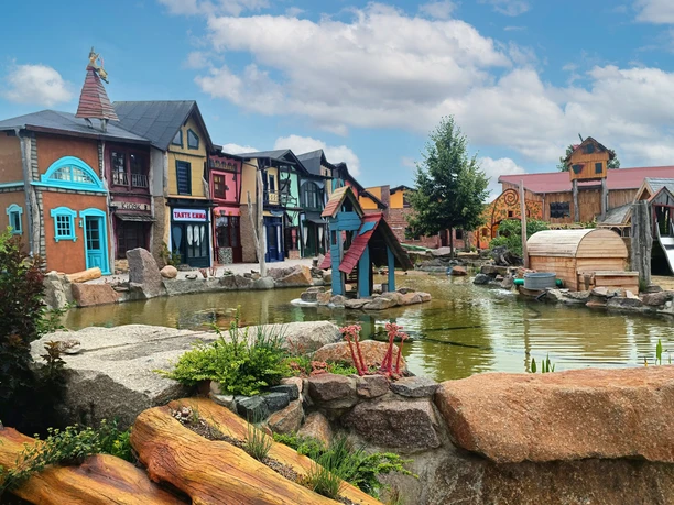ArkaZien Erlebniswelt Region Leipzig - Markthäuser auf dem Marktplatz am Teich Die bunten Fassaden der Markthäuser spiegeln sich im ruhigen Wasser eines Teiches.