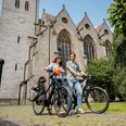 bad-laer-friedensroute-copyright-tol-foto-christoph-steinweg (6).jpg Zwei Menschen mit Fahrrädern vor einer historischen Kirche mit gotischen Fenstern.