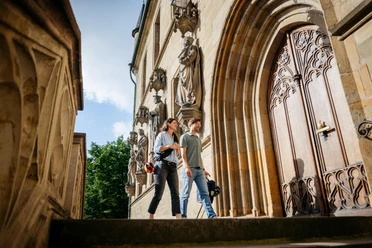 In het historische stadhuis van Osnabrück Twee mensen voor het rijk versierde portaal van het historische stadhuis van Osnabrück, met zijn gotische gevel en stenen figuren.