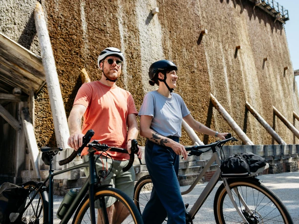 Am Gradierwerk in Bad Rothenfelde Two cyclists with helmets next to bicycles in front of an impressive graduation tower structure.