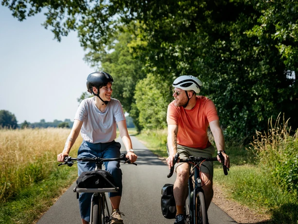 Geniet van fietsen in de regio Osnabrücker Land Twee mannen op fietsen lachen en rijden langs een plattelandsweg.