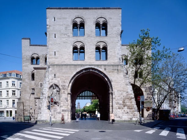 Eigelsteintorburg Südseite Historisches Stadttor mit breitem Durchgang, flankiert von Bäumen und umliegenden Gebäuden.