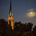 Dreikönigskirche Erleuchteter Kirchturm und Mondsichel bei Nacht.