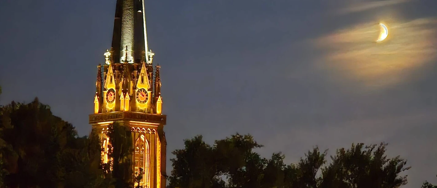 Dreikönigskirche Erleuchteter Kirchturm und Mondsichel bei Nacht.