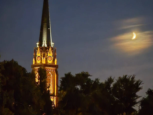 Dreikönigskirche Erleuchteter Kirchturm und Mondsichel bei Nacht.