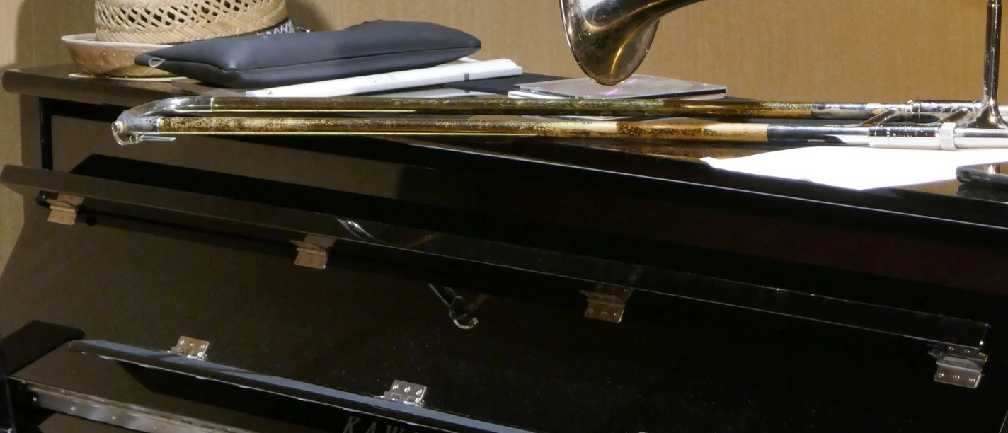 Jazzmusik Auf einem geschlossenen Klavier liegt ein Hut neben einer Trompete und Noten; Musikinstrumente im Fokus.