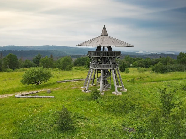 70011-SC-Eggeturm_ © Werner Wilmes.jpg Ein hölzerner Aussichtsturm erhebt sich in einer grünen, leicht hügeligen Landschaft unter bewölktem Himmel.
