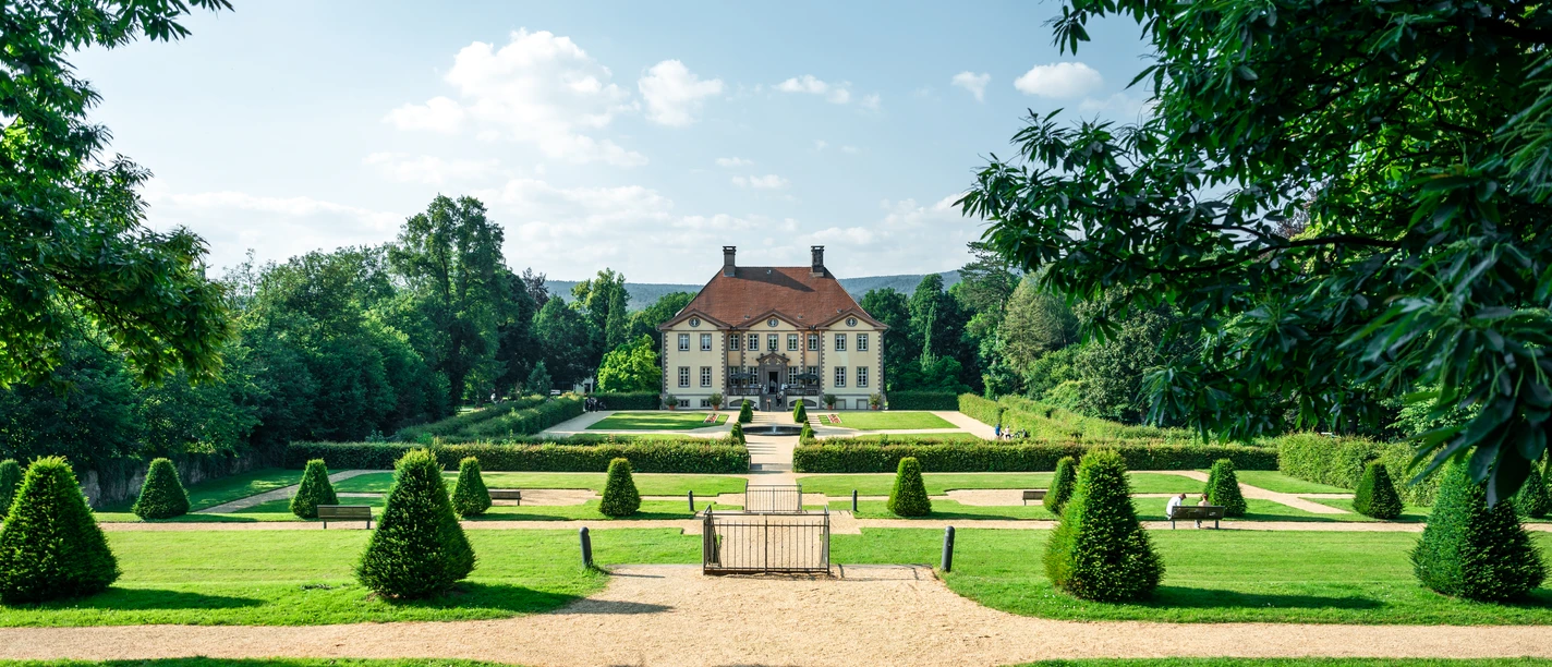 Fotowalk Schloss Schieder(53).jpg Schloss Schieder mit symmetrischem Barockgarten, von saftigem Grün umgeben unter einem klaren Himmel.