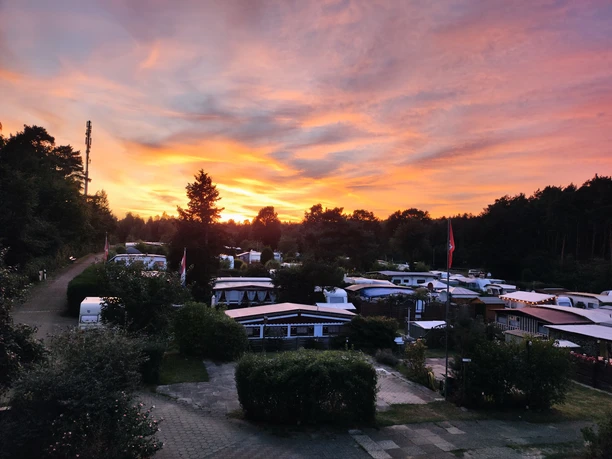 Campingplatz Am Waldschwimmbad_Sonnenuntergang Ein Campingplatz mit Wohnwagen und Zelten bei Sonnenuntergang.