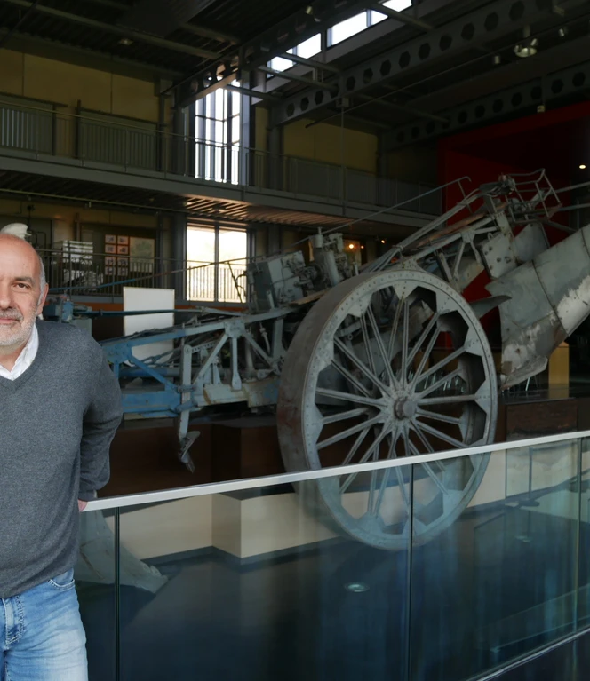 Historiker Ansgar Becker in der Ausstellungshalle II, die die Geschichte des Emslandplans ab 1950 beherbergt. Historiker steht vor landwirtschaftlicher Maschine in moderner Ausstellungshalle zum Emslandplan.