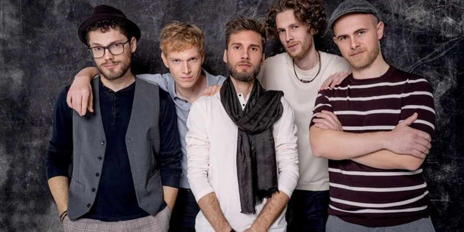 Anders Fünf junge Männer posieren vor einem dunklen Hintergrund. Sie wirken lässig und entspannt.