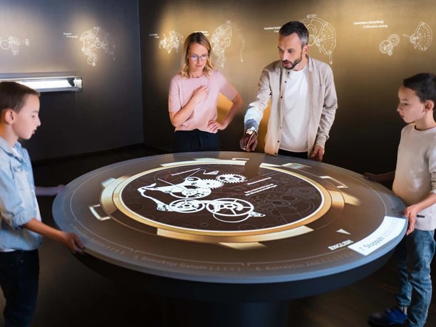 Interaktives Uhrenmodell im Uhrenmuseum Glashuette Familie betrachtet interaktives Display mit astronomischen Informationen im Uhrenmuseum.