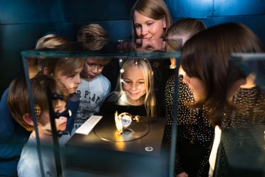 Children are fascinated by an exhibit in a display case in the museum.