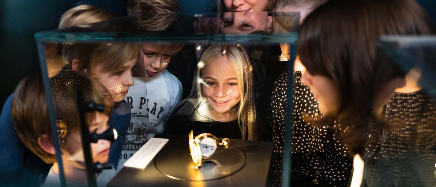 Kinderführung Uhrenmuseum Kinder betrachten fasziniert ein Ausstellungsstück in einer Vitrine im Museum.