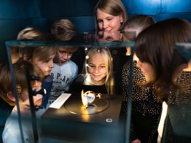 Kinderführung Uhrenmuseum Kinder betrachten fasziniert ein Ausstellungsstück in einer Vitrine im Museum.