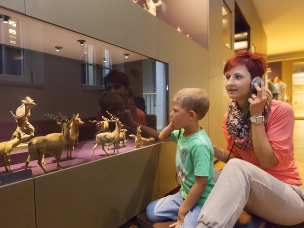 Annaberg-Buchholz_Manufaktur der Träume_Dirk Rückschloss (2).jpg Eine Frau und ein Kind betrachten eine Tierdarstellung in einem Glaskasten im Museum.