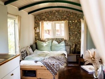 Campingplatz & Tiny Häuser Zur Fähre Ein gemütliches Tiny House: Innenraum mit Bett, Holzdekor und Fenstern auf einem Campingplatz.
