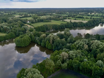 Campingplatz & Tiny Häuser Zur Fähre Kleine Häuser und Zelte stehen harmonisch am Flussufer, umgeben von dichten Wäldern und Feldern.