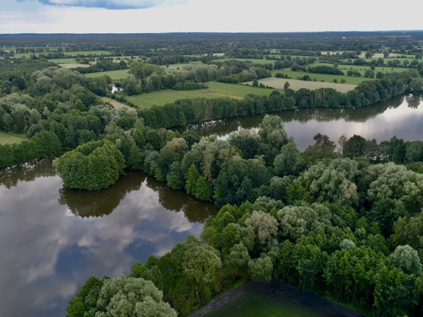 Campingplatz & Tiny Häuser Zur Fähre Kleine Häuser und Zelte stehen harmonisch am Flussufer, umgeben von dichten Wäldern und Feldern.
