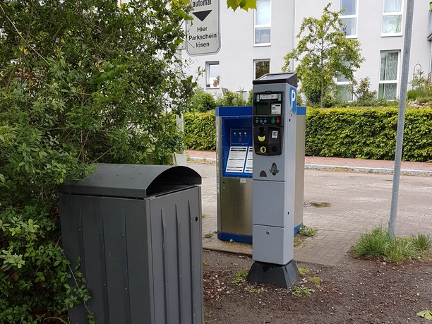 Wohnmobilstellplatz Ratzeburg_Automat Der Wohnmobilstellplatz Ratzeburg verfügt über Parkautomaten und ist umgeben von grünen Pflanzen.