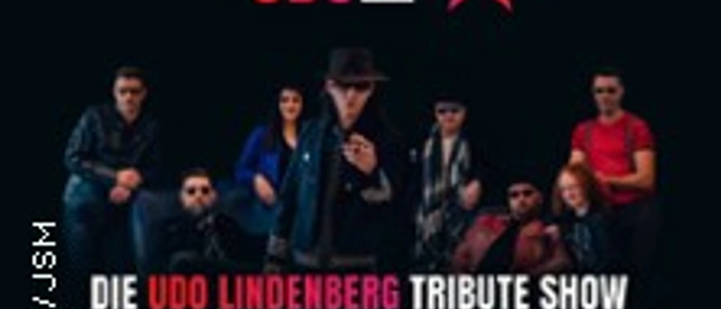 Das Bild zeigt eine Gruppe von neun Personen auf einer Bühne, die für eine Udo Lindenberg Tribute Show posieren.