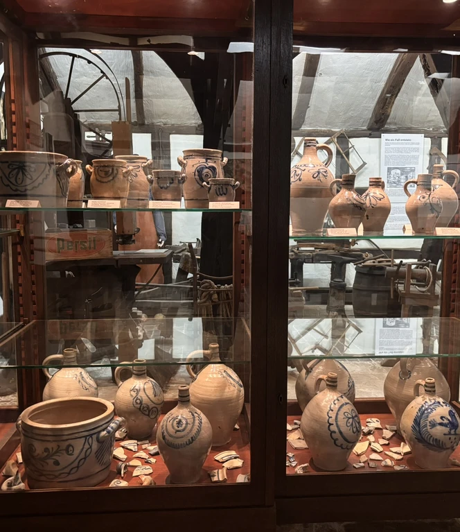 Die Steintopbrennerei ist Bestandteil der Haselünner Geschichte.JPEG Ausstellungsregal mit historischen Tonkrügen und Brennereiobjekten im Museum der Stadt Haselünne