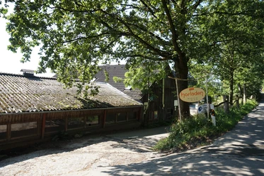 Örkhof mit Hofladen Velbert Eingang zum Örkhof mit Hofladen in Velbert, umgeben von grünen Bäumen und ländlichen Gebäuden.
