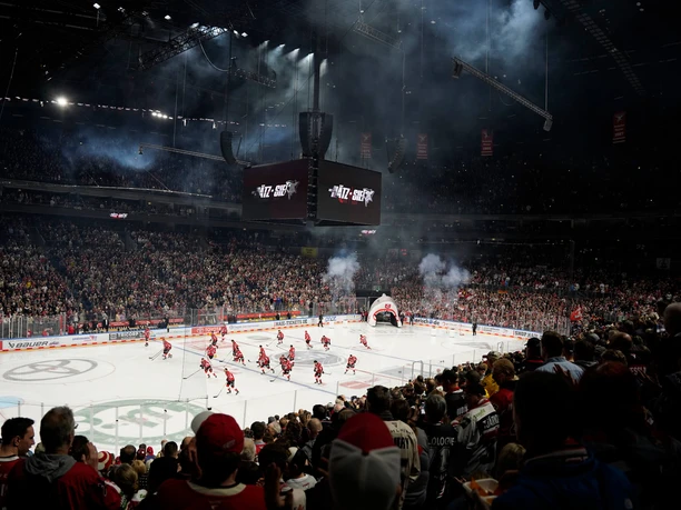 Kölner Haie In a packed ice rink, numerous fans cheer on the Cologne Sharks on the ice, while dynamic lighting and fog effects enhance the atmosphere.