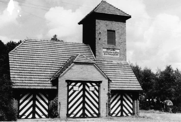 Das alte Spritzenhaus Lahde Historisches Backsteingebäude mit Türmen und gestreiften Toren, umgeben von Bäumen und Himmel.
