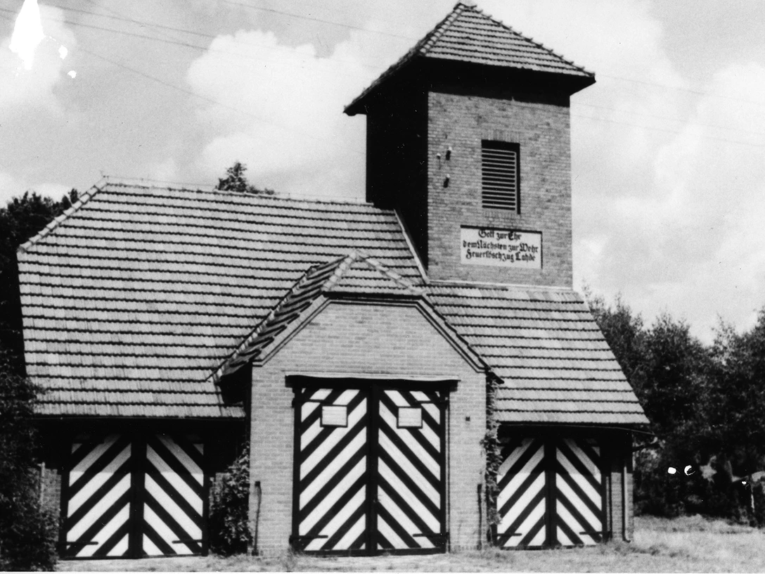 Das alte Spritzenhaus Lahde Historisches Backsteingebäude mit Türmen und gestreiften Toren, umgeben von Bäumen und Himmel.