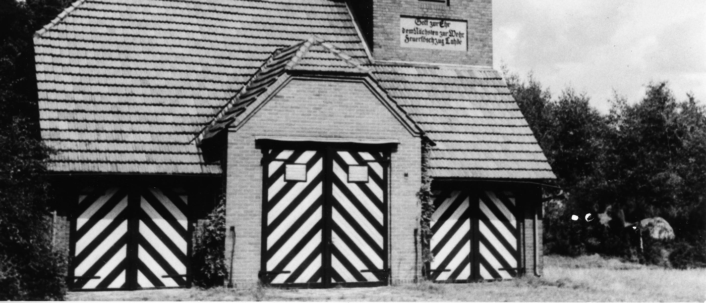 Das alte Spritzenhaus Lahde Historisches Backsteingebäude mit Türmen und gestreiften Toren, umgeben von Bäumen und Himmel.