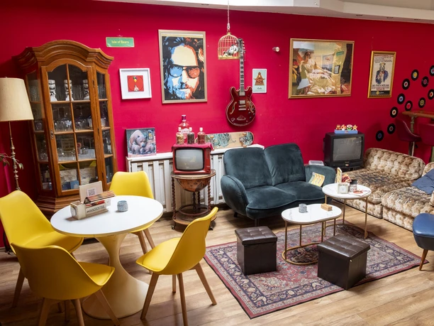 The Bär Das Bild zeigt eine Retro-Lounge, deren Elemente an ein Wohnzimmer der 70er Jahre erinnern.