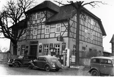 Hotel Tonne Historisches Fachwerkgebäude mit antiken Autos davor; das Hotel Tonne-Logo ziert die Wand.